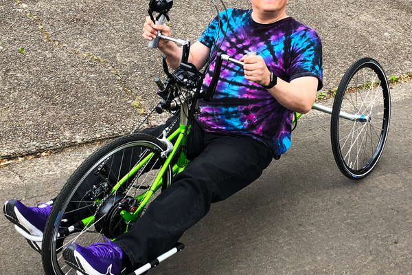Amputee athlete riding a handcycle in a colorful tie-dye shirt