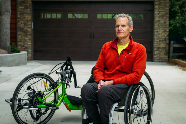 Person with spinal cord injury riding a green handcycle outdoors